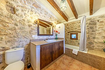 A bathroom with a stone wall and wooden cabinets