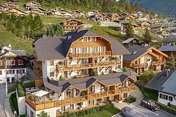 Beautiful wooden chalets and apartments nestled on a green hillside in an alpine resort village.