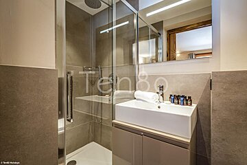 A bathroom with a sink and a shower with the word ten80 on the wall
