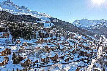 An aerial view of a snowy ski resort with mountains in the background