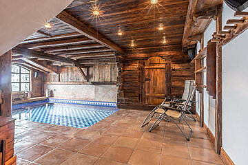 A room with a swimming pool and chairs in it