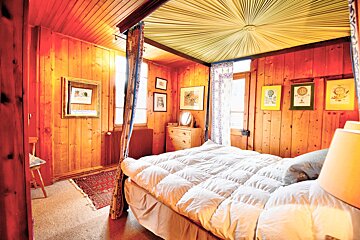 A bedroom with wood paneling and a canopy bed