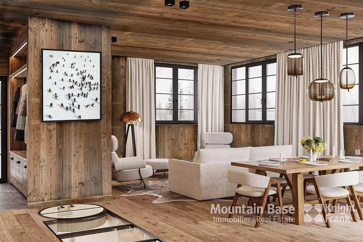 A modern, rustic chalet living and dining room with warm wood paneling, large windows, contemporary furnishings, and a ski-themed wall art.