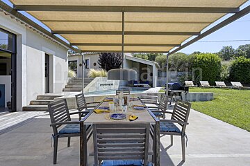 A patio with a table and chairs under a canopy with the word maison in the background