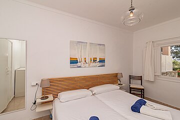 A bedroom with a painting on the wall above the bed