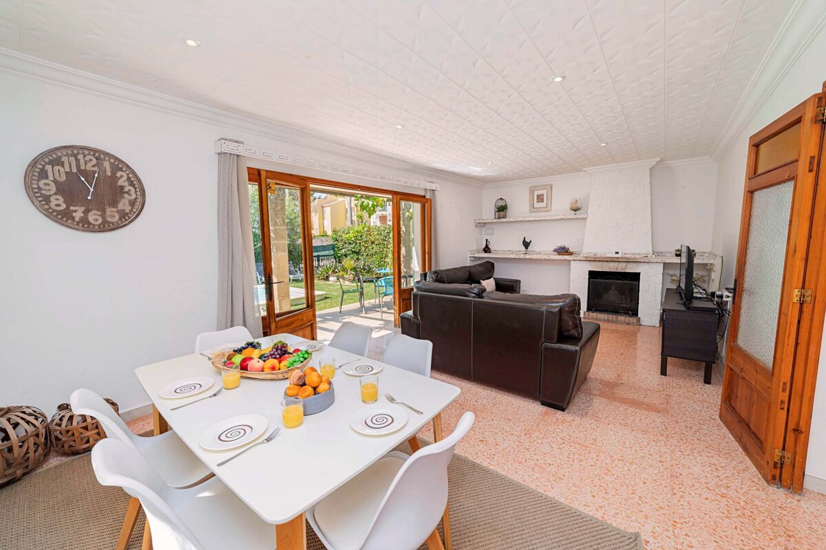 A living room with a table and chairs and a clock on the wall