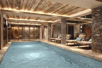 Luxurious indoor pool area with stone pillars, a wood-beamed ceiling, warm ambient lighting, and poolside lounge chairs.
