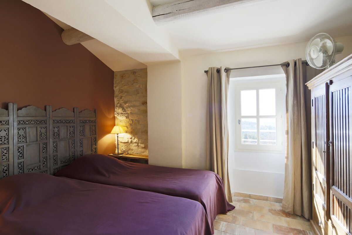 A bedroom with two beds and a fan on the wall