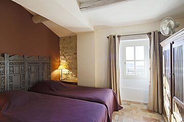 A bedroom with two beds and a fan on the wall