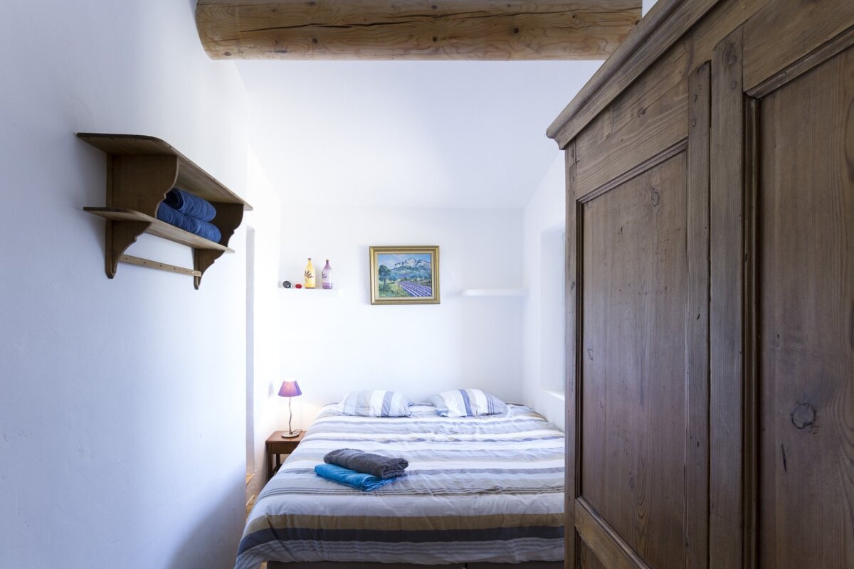 A bedroom with a painting on the wall above the bed