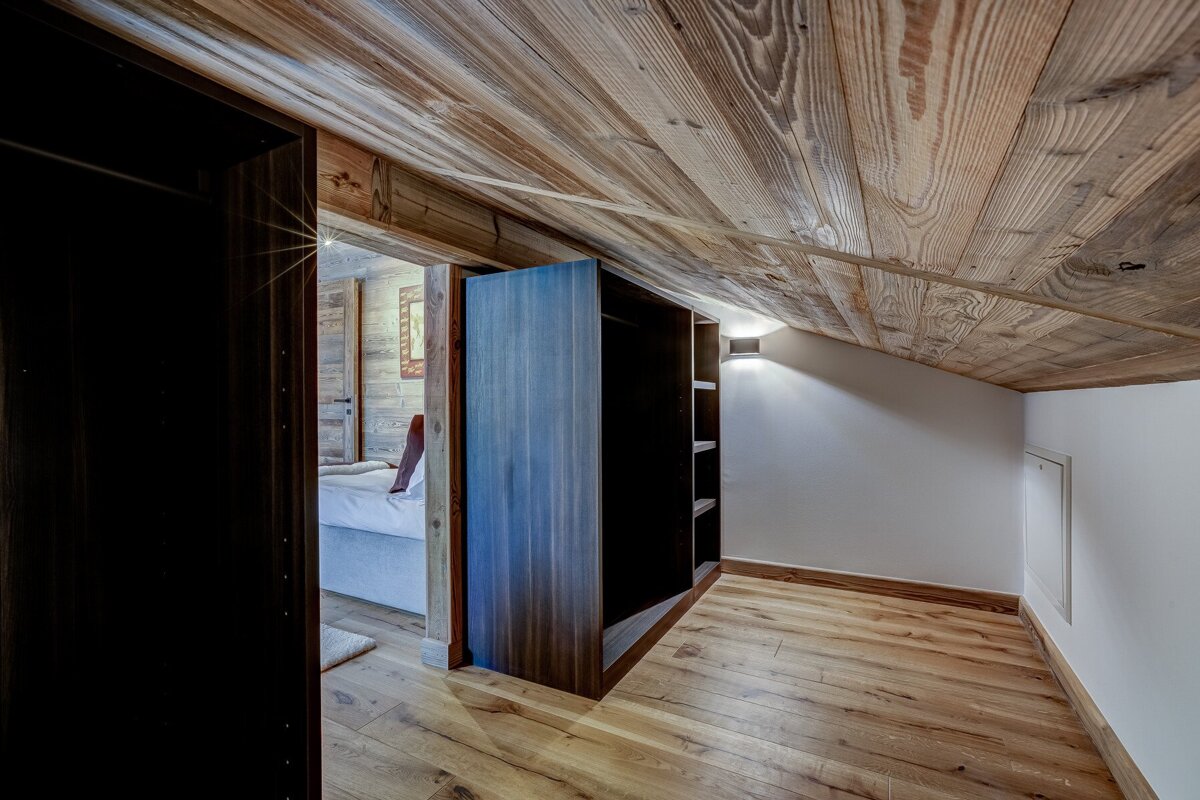 A bedroom with a wooden ceiling and hardwood floors