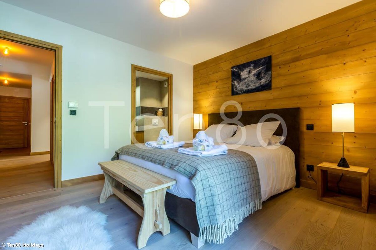 A bedroom with a bed and a bench and the word terra on the wall