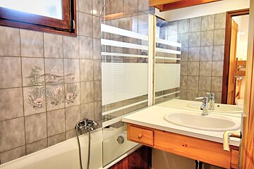 A bathroom with a sink and a bathtub with flowers on the tiles