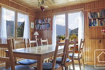 A dining room with a table and chairs and a bookshelf with books on it