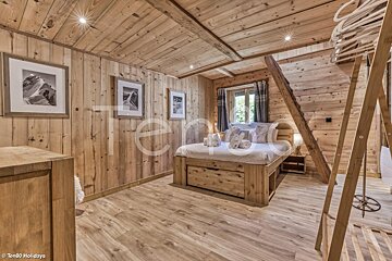 A bedroom in a wooden cabin with a bed and a ladder