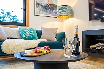 A bottle of champagne sits on a table next to two glasses