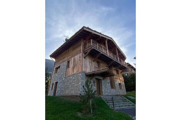 A large stone and wooden house with stairs leading up to it