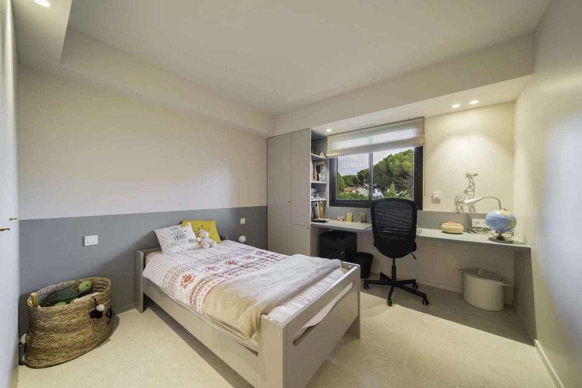 Bright, modern child's bedroom with a bed, desk under a window, and gray and white walls.
