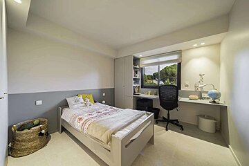 Bright, modern child's bedroom with a bed, desk under a window, and gray and white walls.