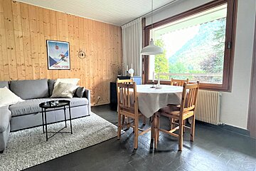 A living room with a table and chairs and a ski poster on the wall