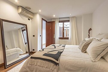 A bedroom with a bed and a large mirror