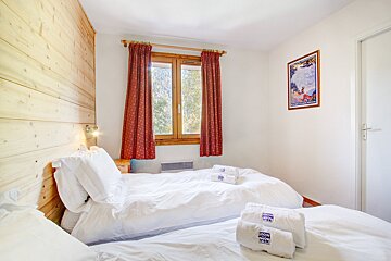 A bedroom with two beds and a picture on the wall