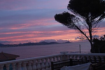 A sunset over the ocean with mountains in the background