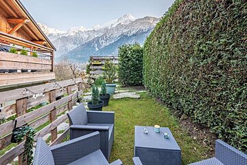 A patio area with chairs and a table with mountains in the background