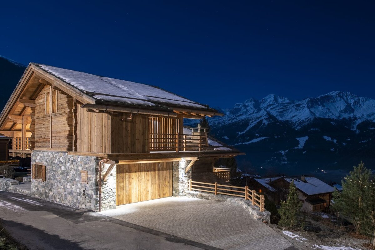 A snowy mountain is visible behind a wooden house