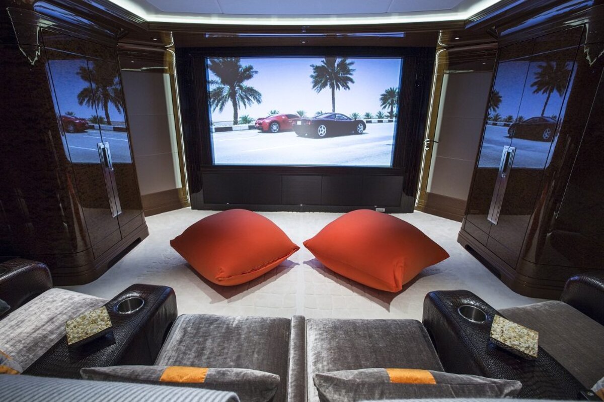 A projector screen shows two cars driving on a beach