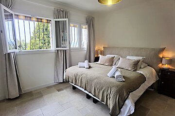 A bedroom with a large bed and two windows