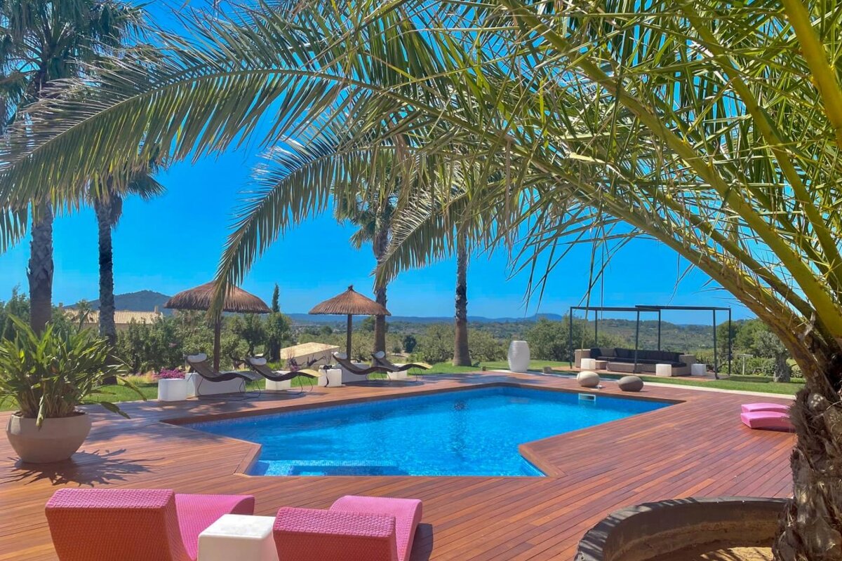 A large swimming pool surrounded by palm trees and chairs