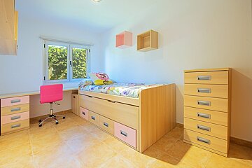 A bedroom with a bed and a pink chair