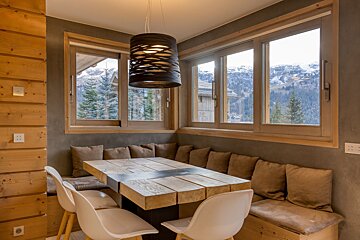A dining room with a wooden table and white chairs