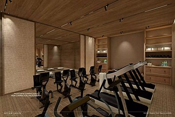 Warm-toned fitness room with treadmills, stationary bikes, and yoga mats. Features wood ceilings/walls, track lighting, and amenity shelves.