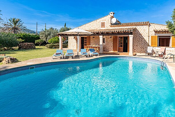 A large swimming pool in front of a stone house