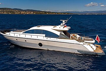 A white yacht is floating in the ocean with mountains in the background