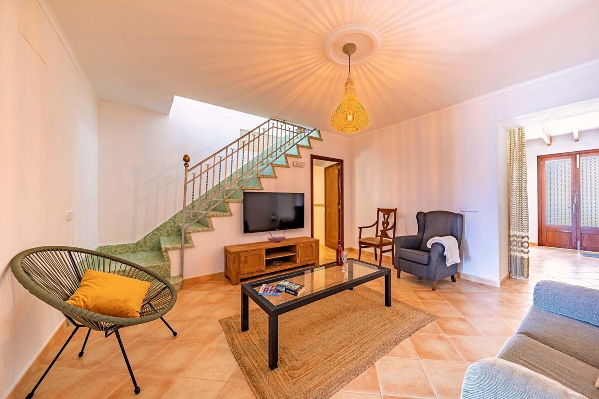A living room with a staircase and a flat screen tv