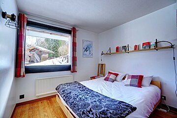 A bedroom with a bed and a shelf with books on it