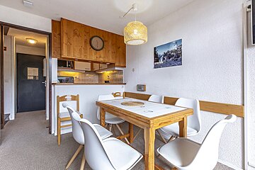 A kitchen with a table and chairs and a clock on the wall