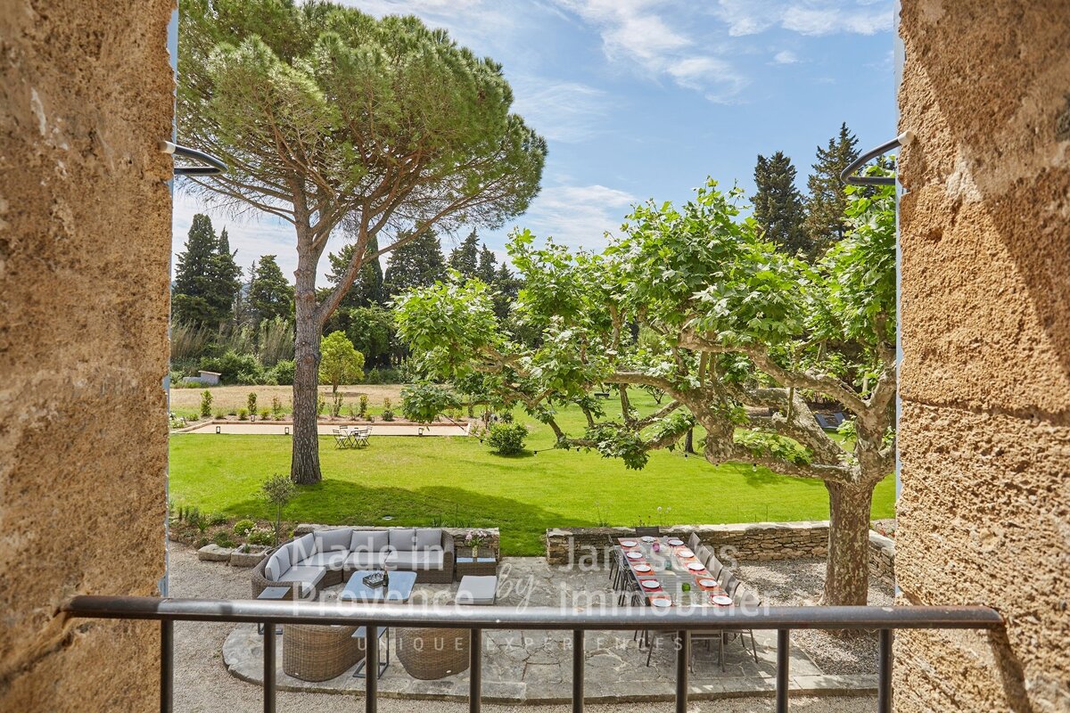 A balcony with a view of a lush green field and a table with plates on it