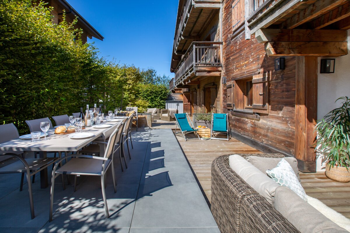 A patio with a table and chairs in front of a wooden building