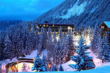 A snowy forest with a building in the background