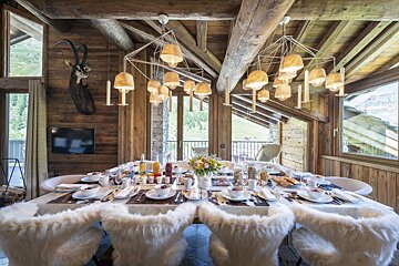 A large wooden dining room with a table set for a meal