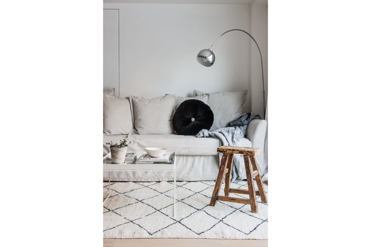 A living room with a white couch and a black pillow