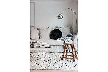 A living room with a white couch and a black pillow