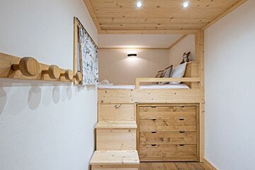 A wooden bunk bed with a dresser underneath it