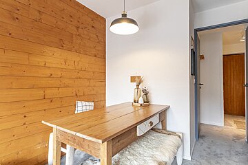 A wooden table with a white drawer sits in front of a wooden wall