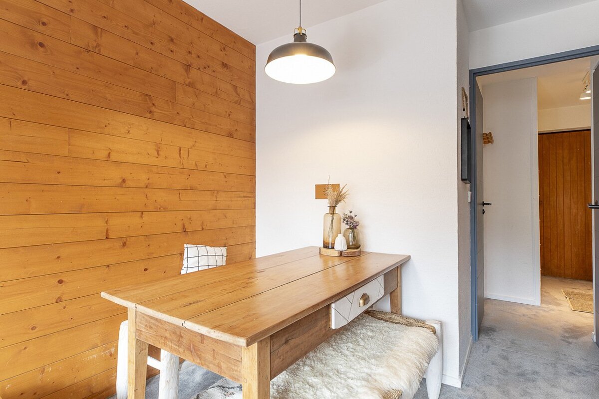 Cozy dining nook with a wooden plank accent wall, rustic wooden table, fuzzy bench, and an industrial-style pendant light.