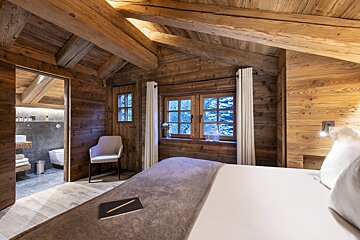 A bedroom in a wooden cabin with a bed and chair